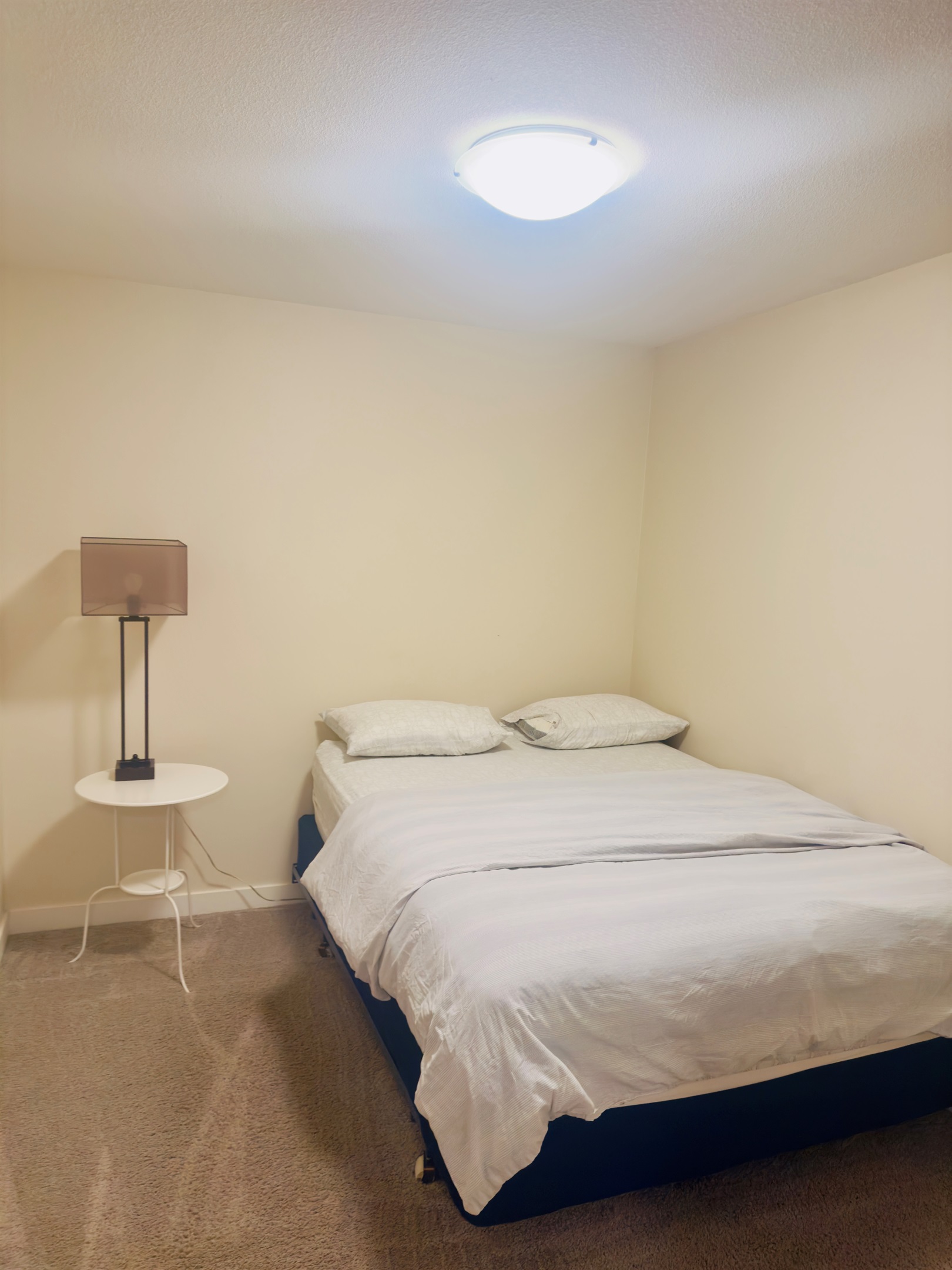 Cozy minimalist bedroom with queen bed, soft lighting, full closet, clean comfort.