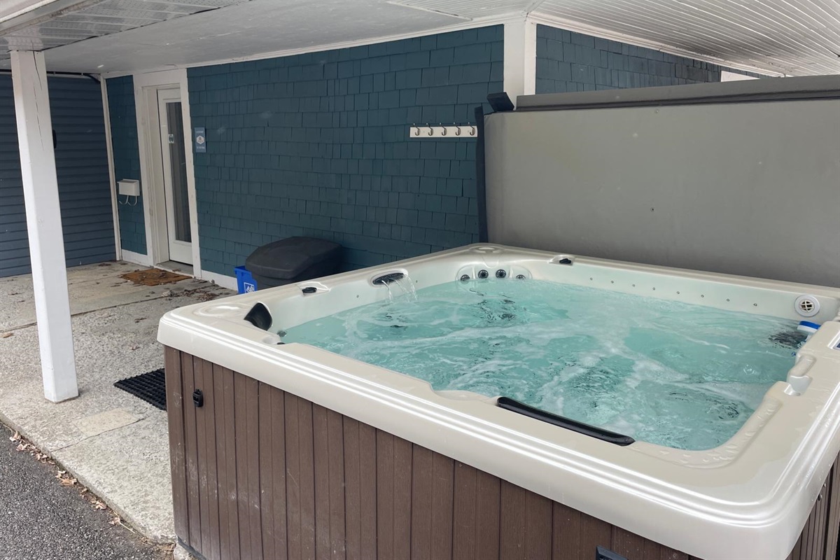 Hot Tub with cover fully back and view of Veranda with hooks for robes on wall behind