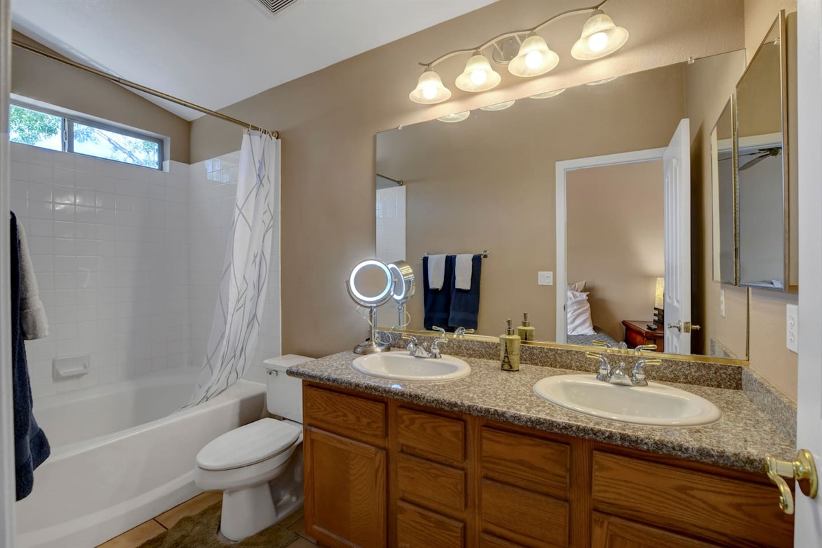 Bright bath with double vanity, tub/shower, and ample counter space