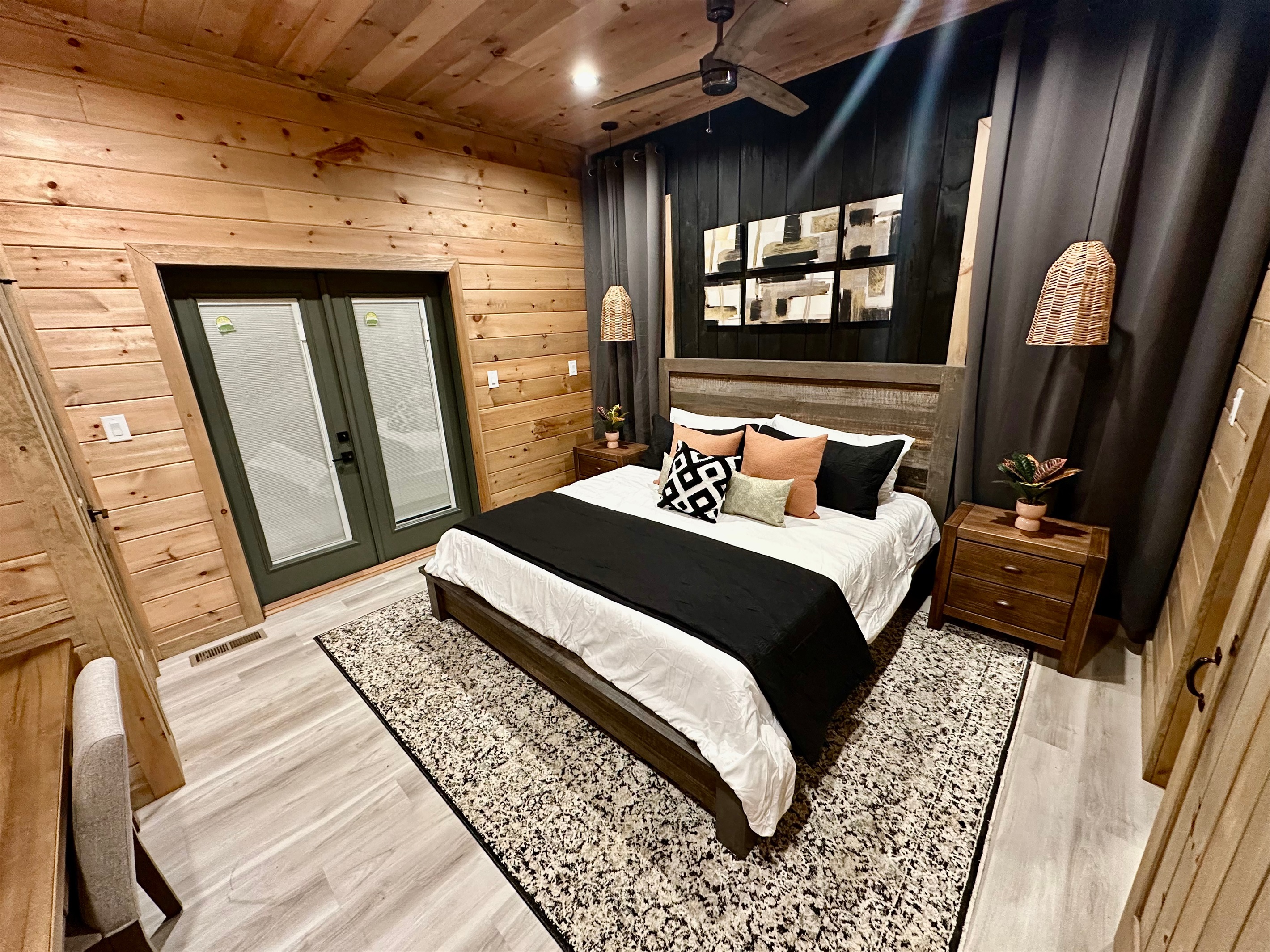 A cozy king retreat with warm wood walls, layered textures, and soft lighting. Sliding doors open to fresh mountain air, creating the perfect space for slow nights and restful mornings tucked in the trees.