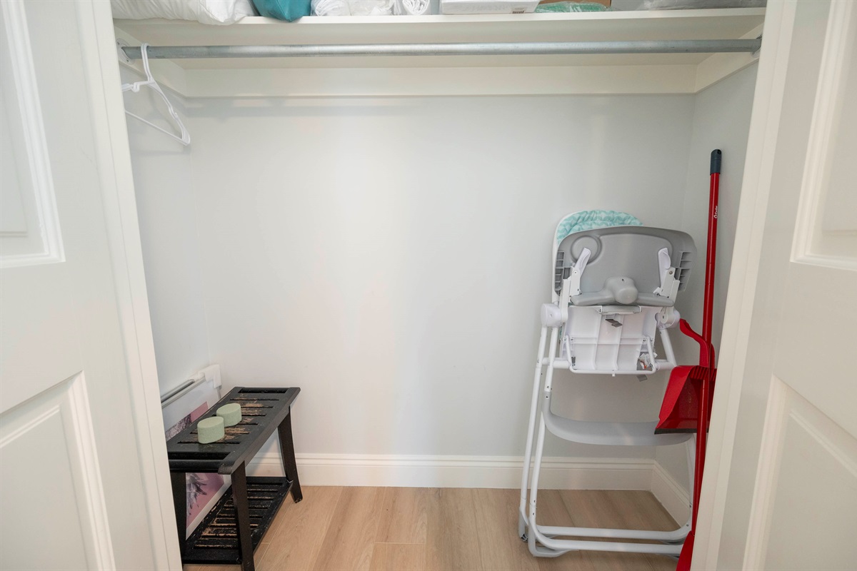 Organized closet with baby high chair, storage bench, and neat essentials.