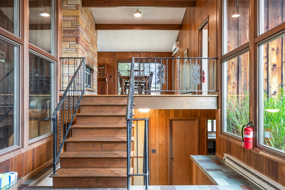 Step into warmth with soaring windows, wood-paneled walls, and a charming stone fireplace that welcomes you into this inviting retreat.