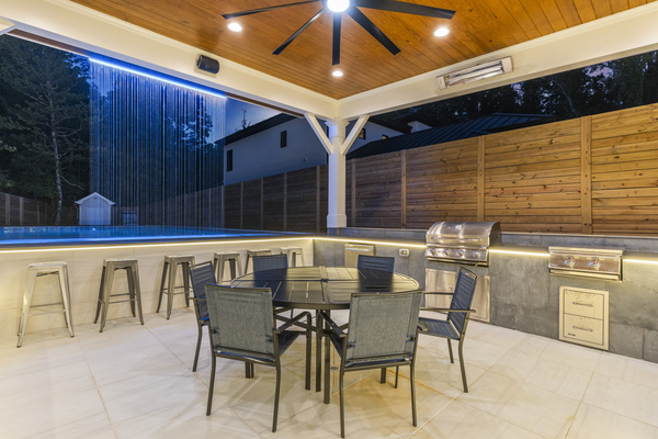 Large covered gazebo area with outdoor kitchen and dining area, heat lamps, surround sound, large tv, and bar stools by the hot tub swim up bar. 