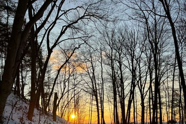 Stroll down this magical snow-dusted trail lined with towering trees as the sun sets over Lake Michigan. A perfect moment of winter calm and natural beauty