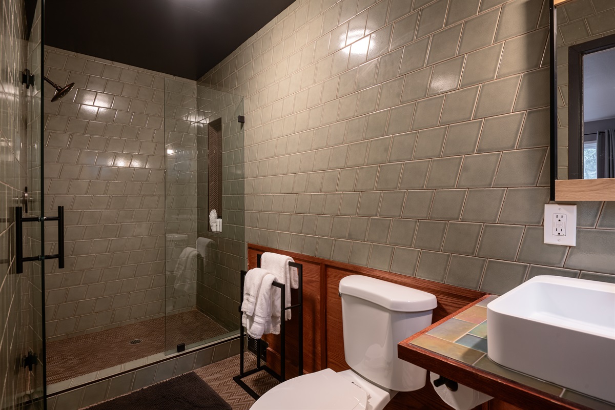 Stylish tiled bathroom with a spacious walk-in shower and warm wood accents—modern design with a cozy cabin feel.