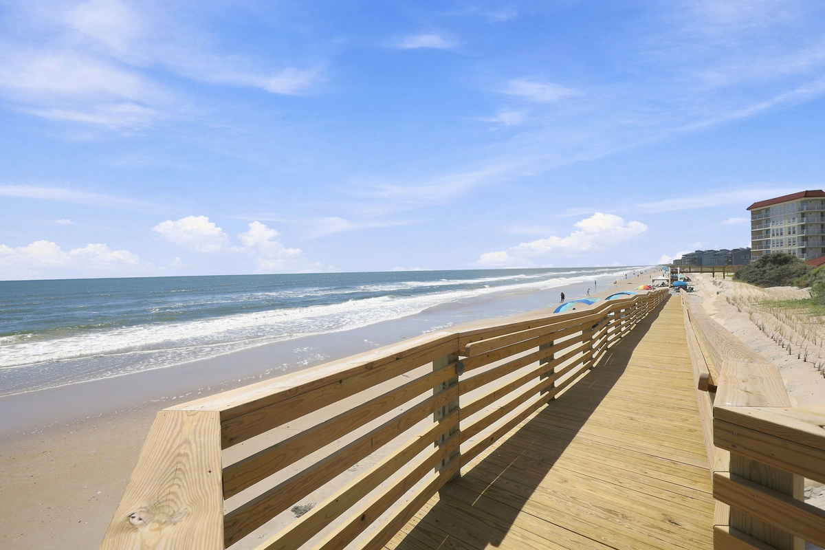 Wooden boardwalk leading directly from the resort down to the sandy shoreline and ocean waves.