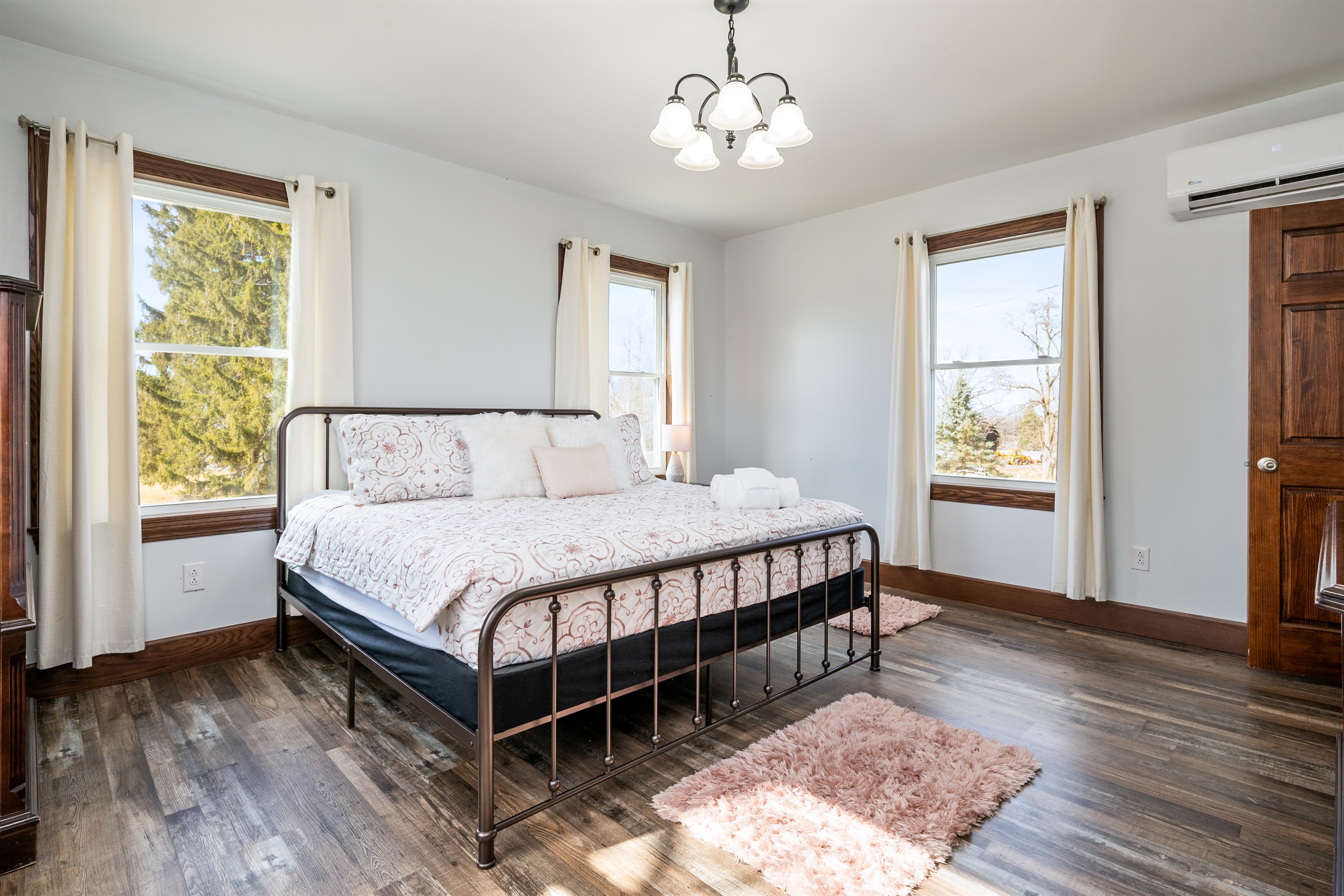 Primary bedroom with queen bed, natural light, and peaceful upstate New York views.