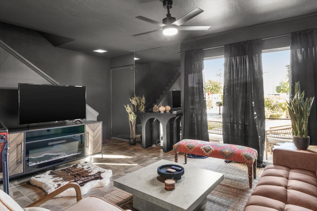 Cozy living room with a Smart TV, fireplace console, soft seating, and patio doors nearby.