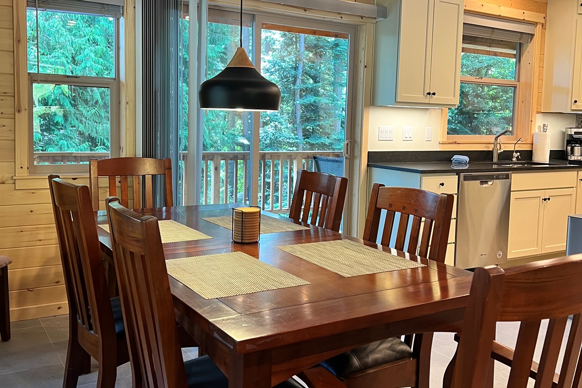 Dining area with seating for six people and sliding glass doors that lead to additional seating on outside deck.
