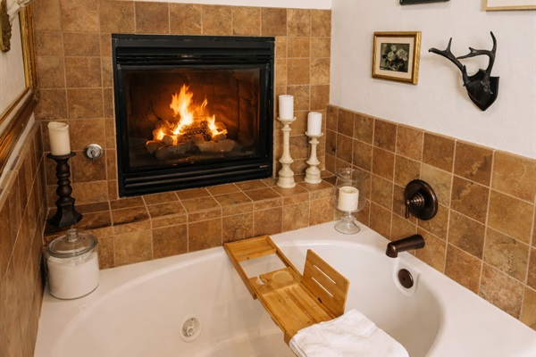 Candlelit jetted tub beside a cozy fireplace—perfect for slow evenings, wine, and total relaxation after a day in the mountains.