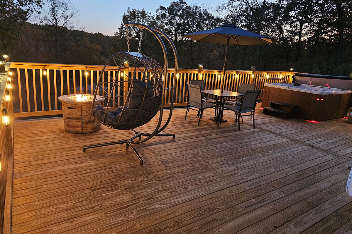 Romantic evening deck with fire pit, hot tub, hanging chair, and soft ambient lighting — your private luxury escape