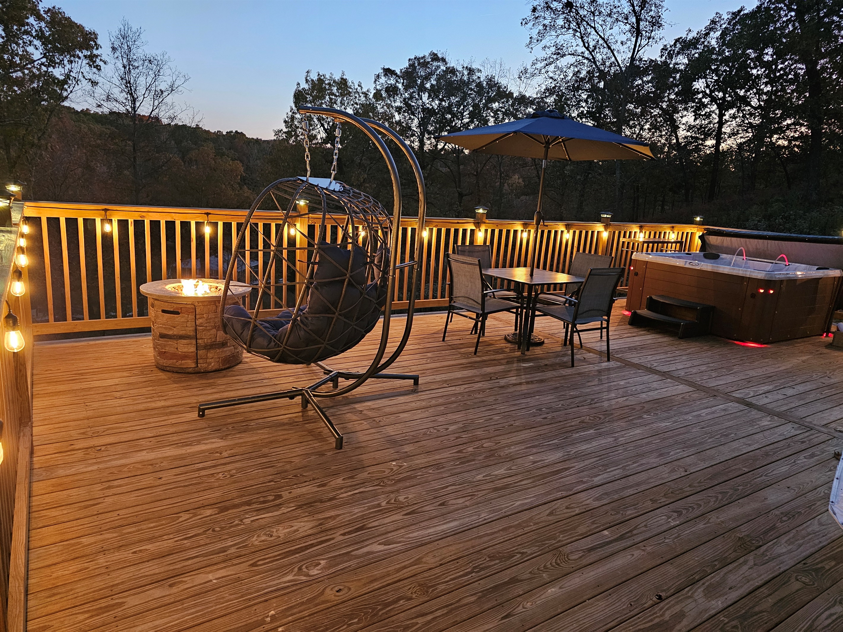 Romantic evening deck with fire pit, hot tub, hanging chair, and soft ambient lighting — your private luxury escape