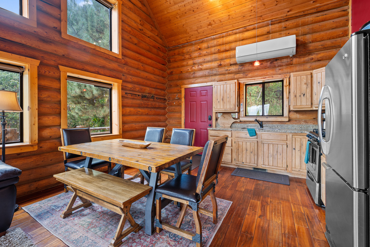 Bright dining and kitchen area framed by warm log walls and plentiful windows.