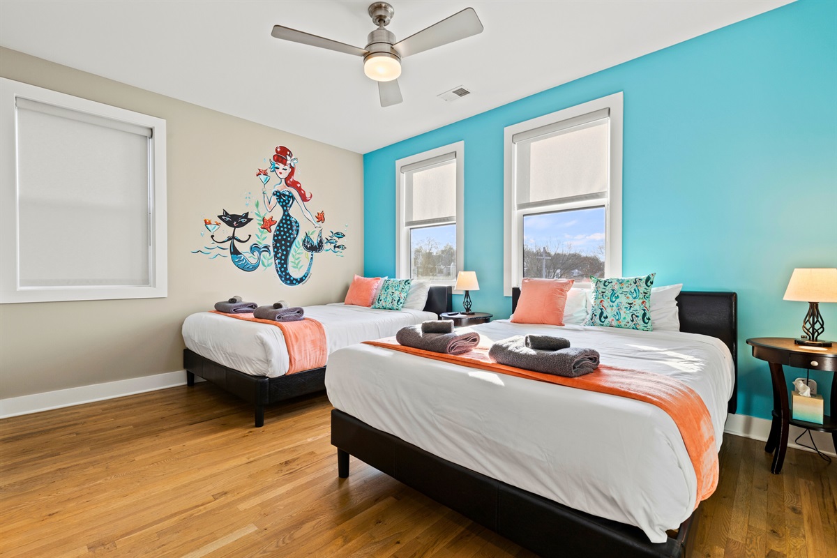 Casa Tiffani’s mermaid bedroom offers two elegant queen beds, bedside tables with lamps, and a fun mermaid mural.