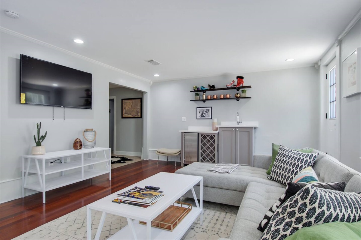 Living room with sectional sofa, wet bar, big screen smart tv, and rear courtyard access.