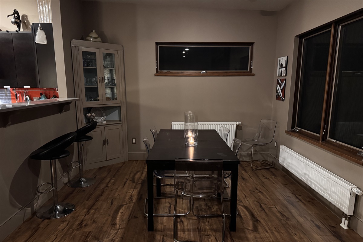 Spacious dining area with seating for six, plus additional breakfast bar seating for two. Large windows overlook the massive backyard, 33ft deck, and fire pit area, perfectly blending indoor dining with the Acadia wilderness outside.