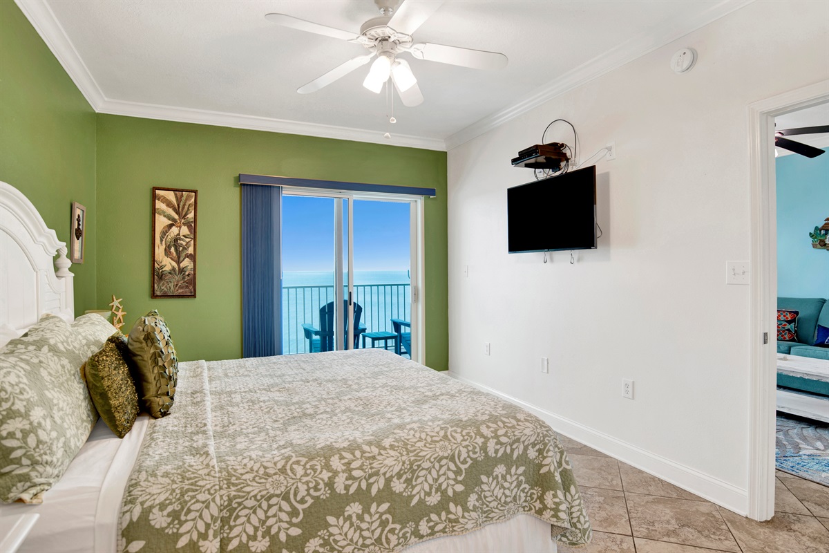 Master bedroom with a king bed, 2 nightstands, ceiling fan, wall mounted 43" Smart TV, direct balcony access, beautiful view of the Gulf and on suite master bathroom.