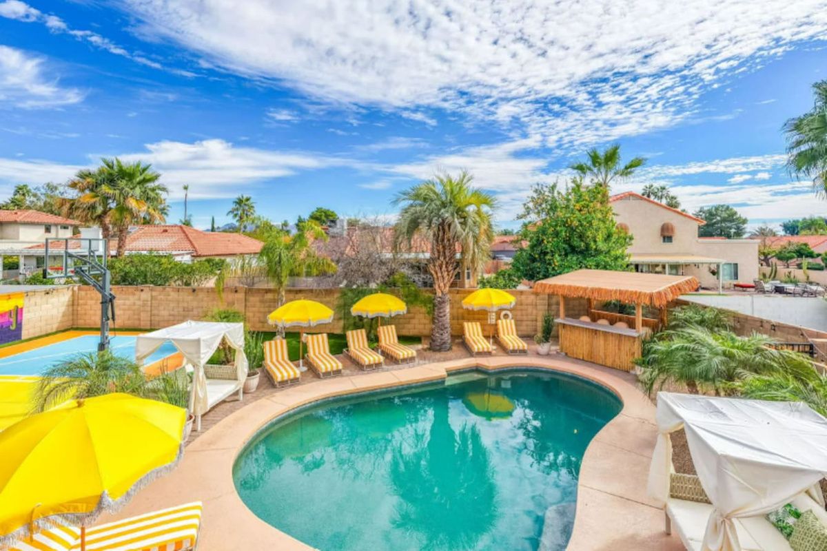 Resort-style pool area with loungers, yellow umbrellas, and desert views—a vacation oasis steps from the home.