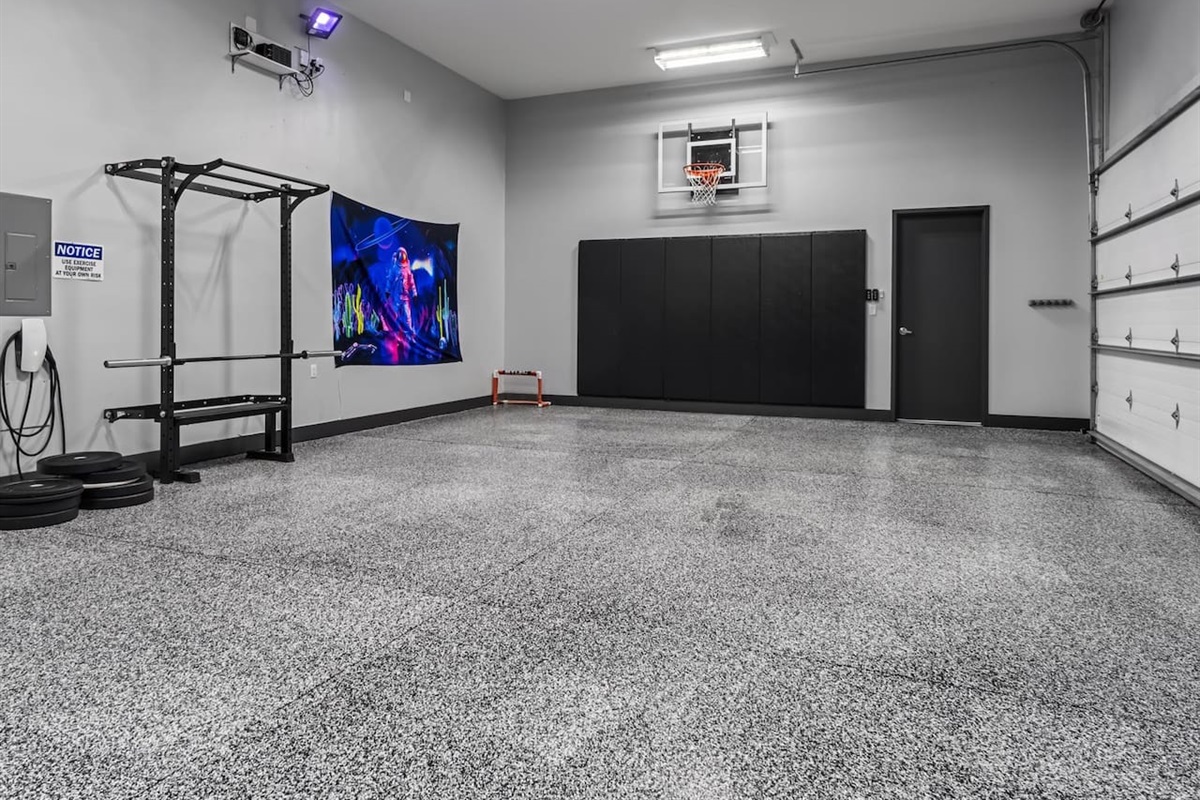 Garage with tesla car charger, pro basketball hoops, gym equipment and barbells, glow in the dark dodgeball, street hockey, ping pong, paddleboard and more. 
