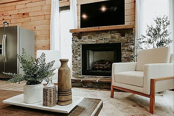 Cozy up in the living room where soft lighting, warm wood, and a crackling fire make every night feel special