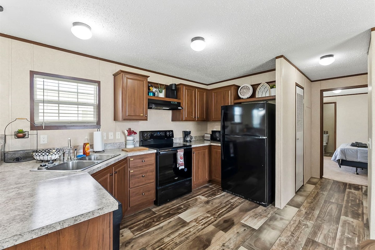 Spacious kitchen with wraparound counters, black appliances, and direct access to nearby bedrooms for added convenience.