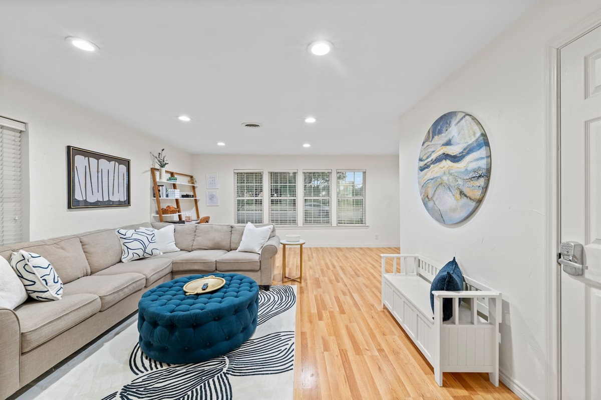 Bright and inviting with large windows, a plush sectional, and curated modern decor for a chic yet comfortable vibe.