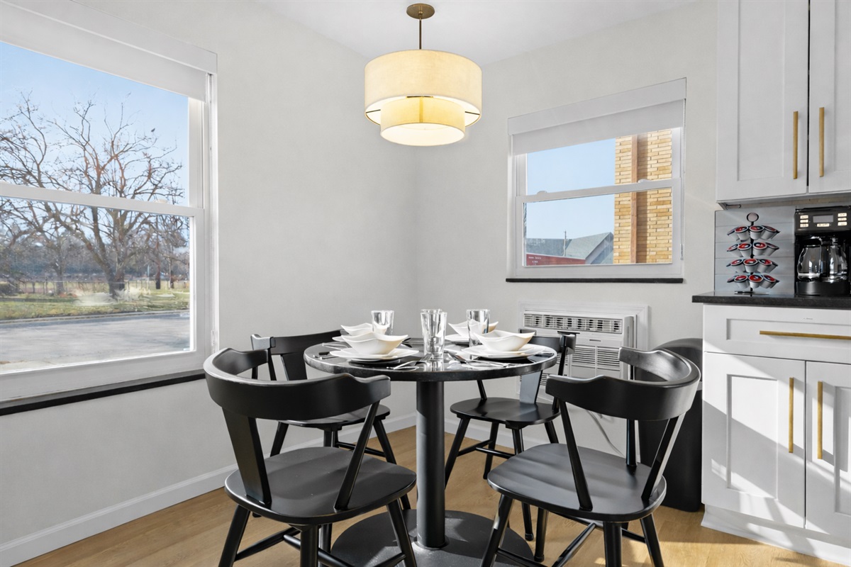 Enjoy meals in this sunlit dining area with modern seating, warm lighting, and a fully stocked kitchen—perfect for relaxed breakfasts or evening dinners.