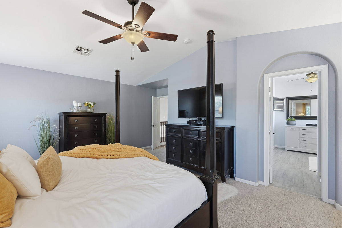Primary bedroom with king bed, dresser storage, TV, and direct access to the ensuite bathroom.