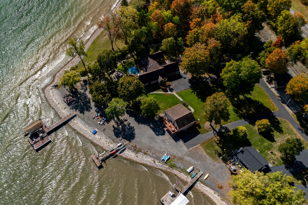 Aerial view of your quiet waterfront retreat surrounded by vibrant fall foliage. Peace, privacy, and lake access all in one.