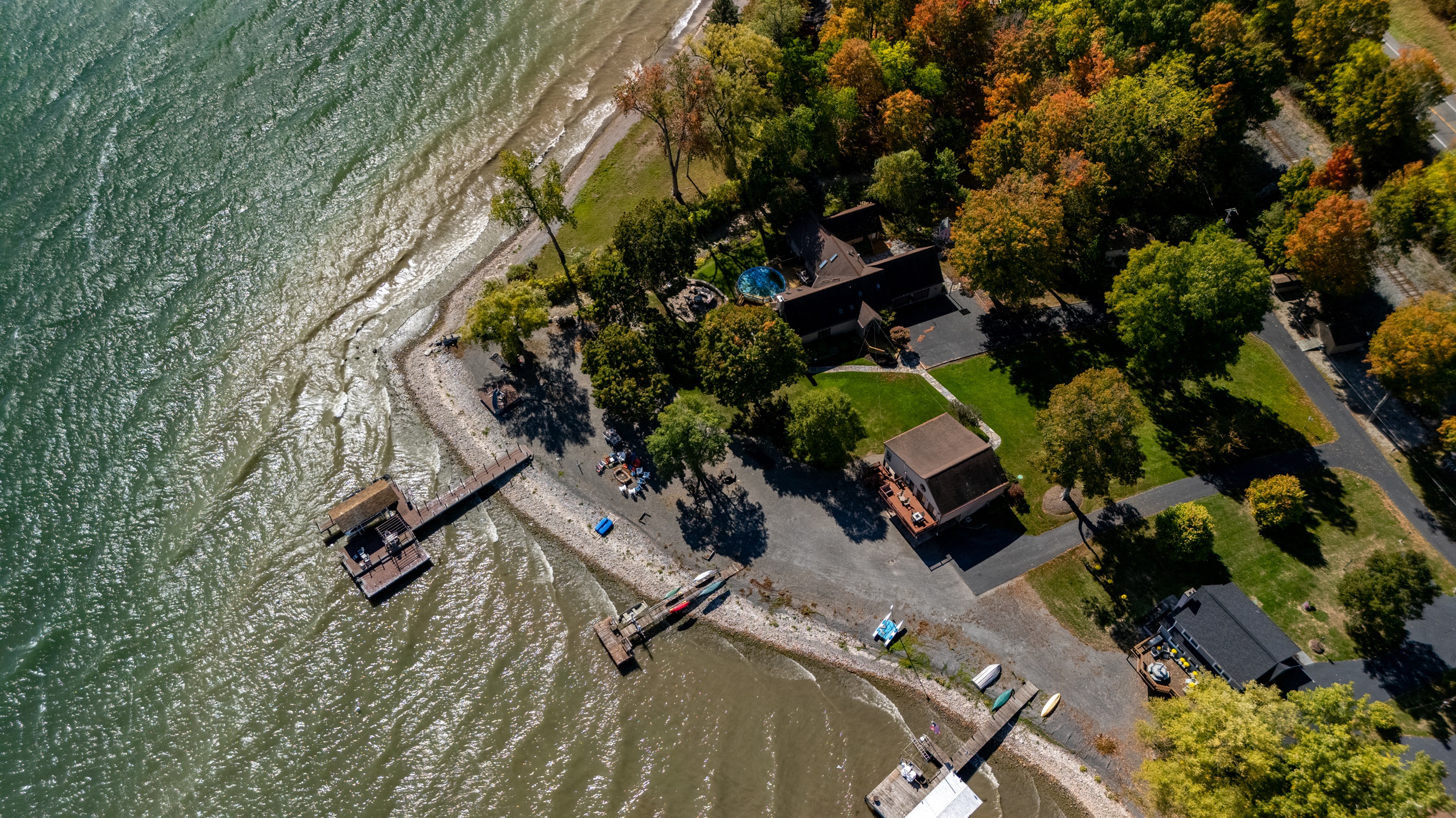 Aerial view of your quiet waterfront retreat surrounded by vibrant fall foliage. Peace, privacy, and lake access all in one.