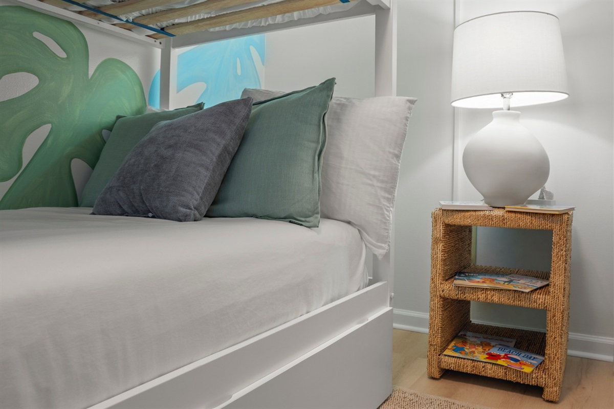 Sink into soft pillows and drift off beneath calming tropical tones, where cozy textures and gentle lighting end a beach-filled day perfectly.