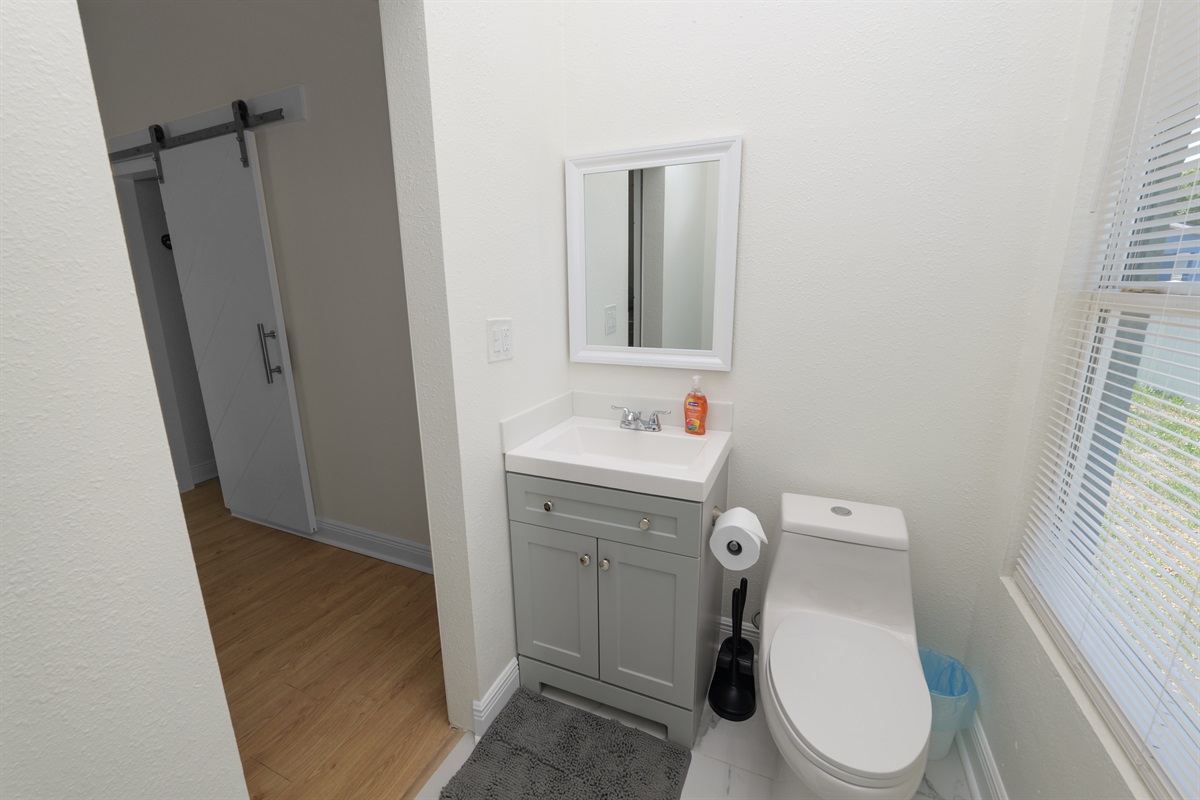 Modern and efficient, this light-filled bathroom includes a curved glass shower with spa-style amenities, plush white towels, and a window that welcomes natural light while maintaining privacy.