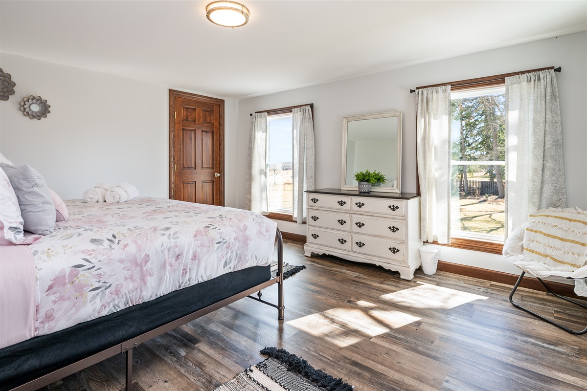 Spacious bedroom with large windows, a comfy queen bed, and a calm, airy design that creates the perfect retreat for rest and rejuvenation.