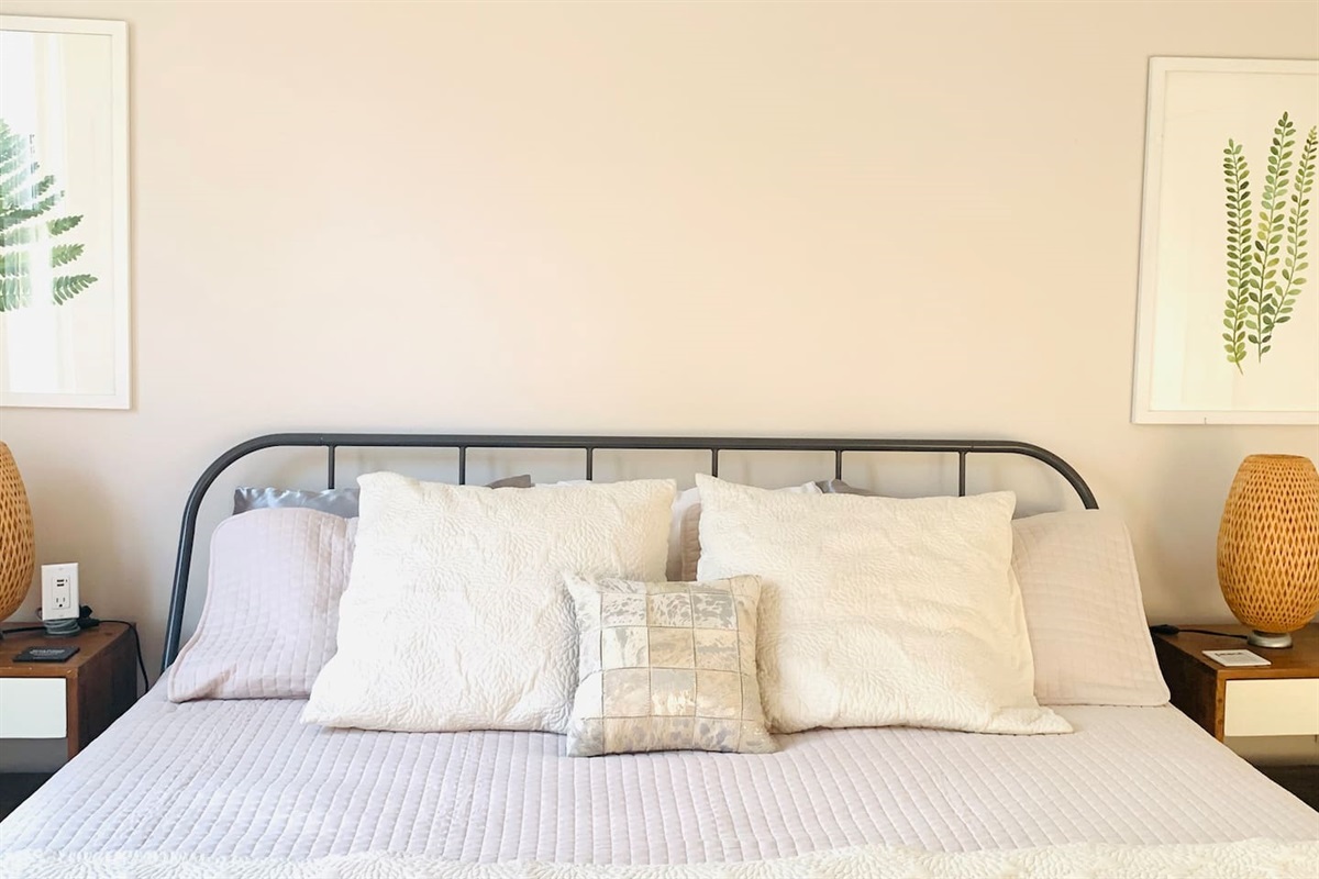 Serene primary bedroom featuring king size comfortable bed, soft cotton linens, warm ambient lighting and blackout shades - designed for calm and rest. 