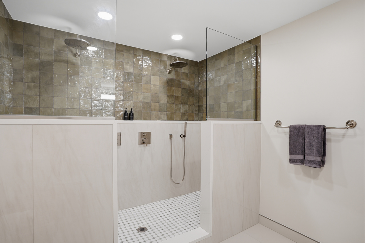 Modern spa-style walk-in shower with elegant stone tile, glass partition, and built-in bench. Bright, clean, and designed for a relaxing, hotel-like experience.