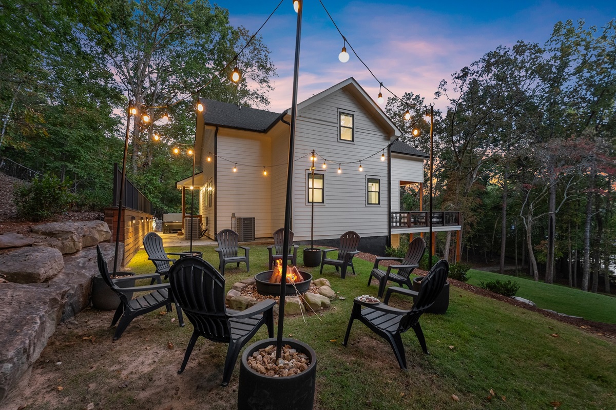 Fire pit with string lights and Adirondack chairs.