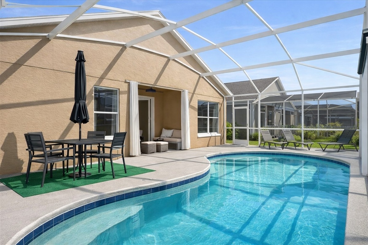 Relax by the private pool with outdoor seating in a bright screened patio.