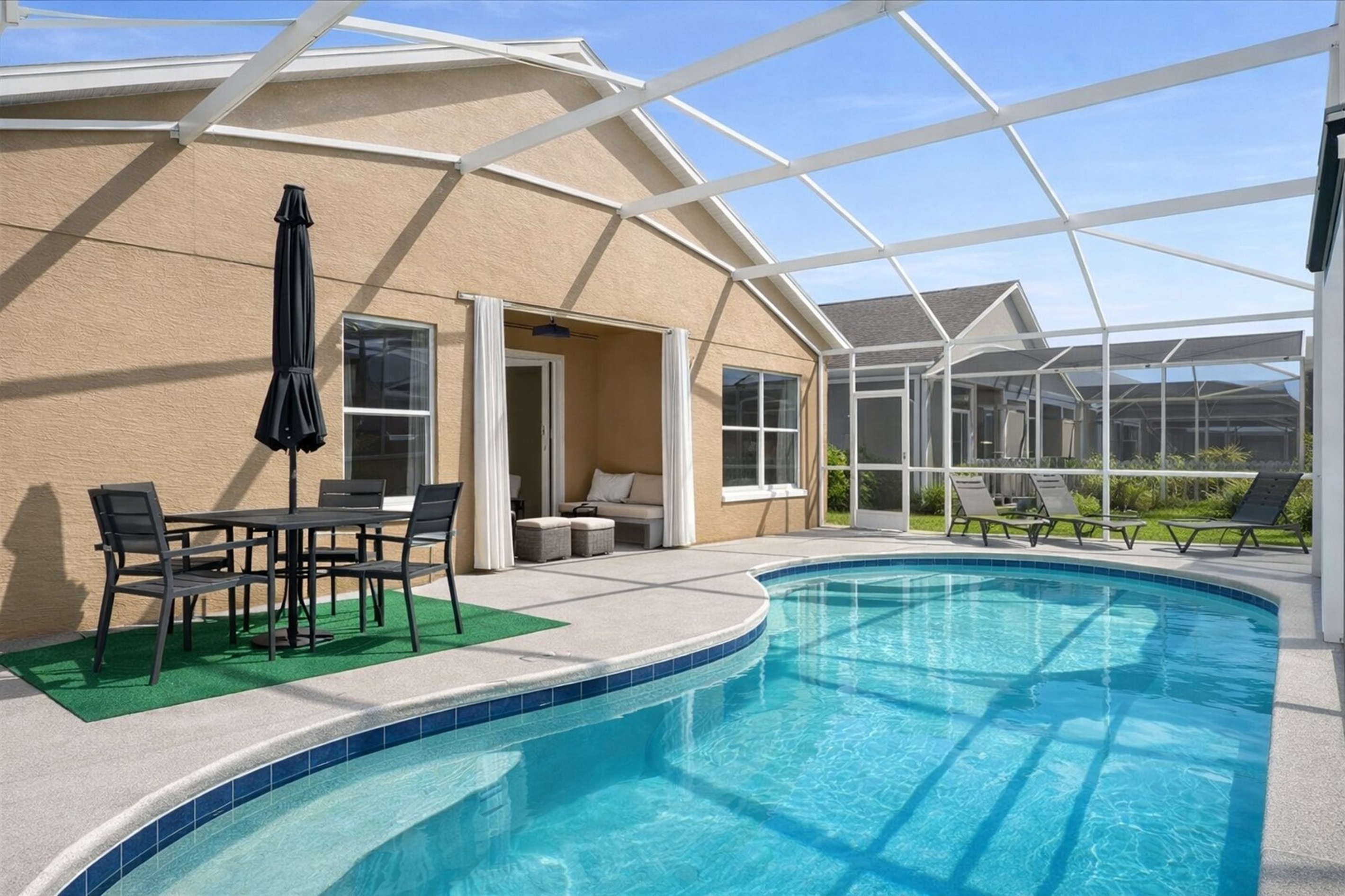 Relax by the private pool with outdoor seating in a bright screened patio.