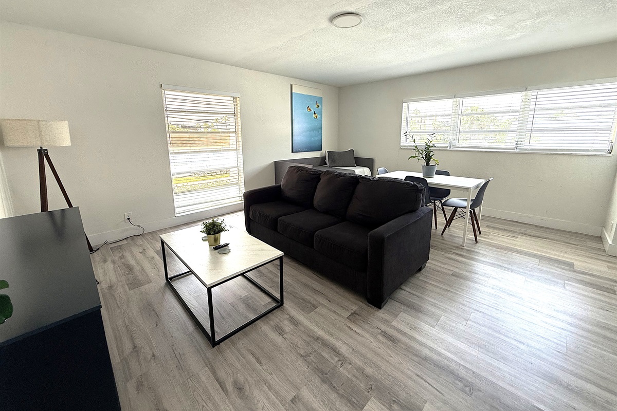 Wide view of living room and dining area. A queen sofa bed that sleeps two guests.