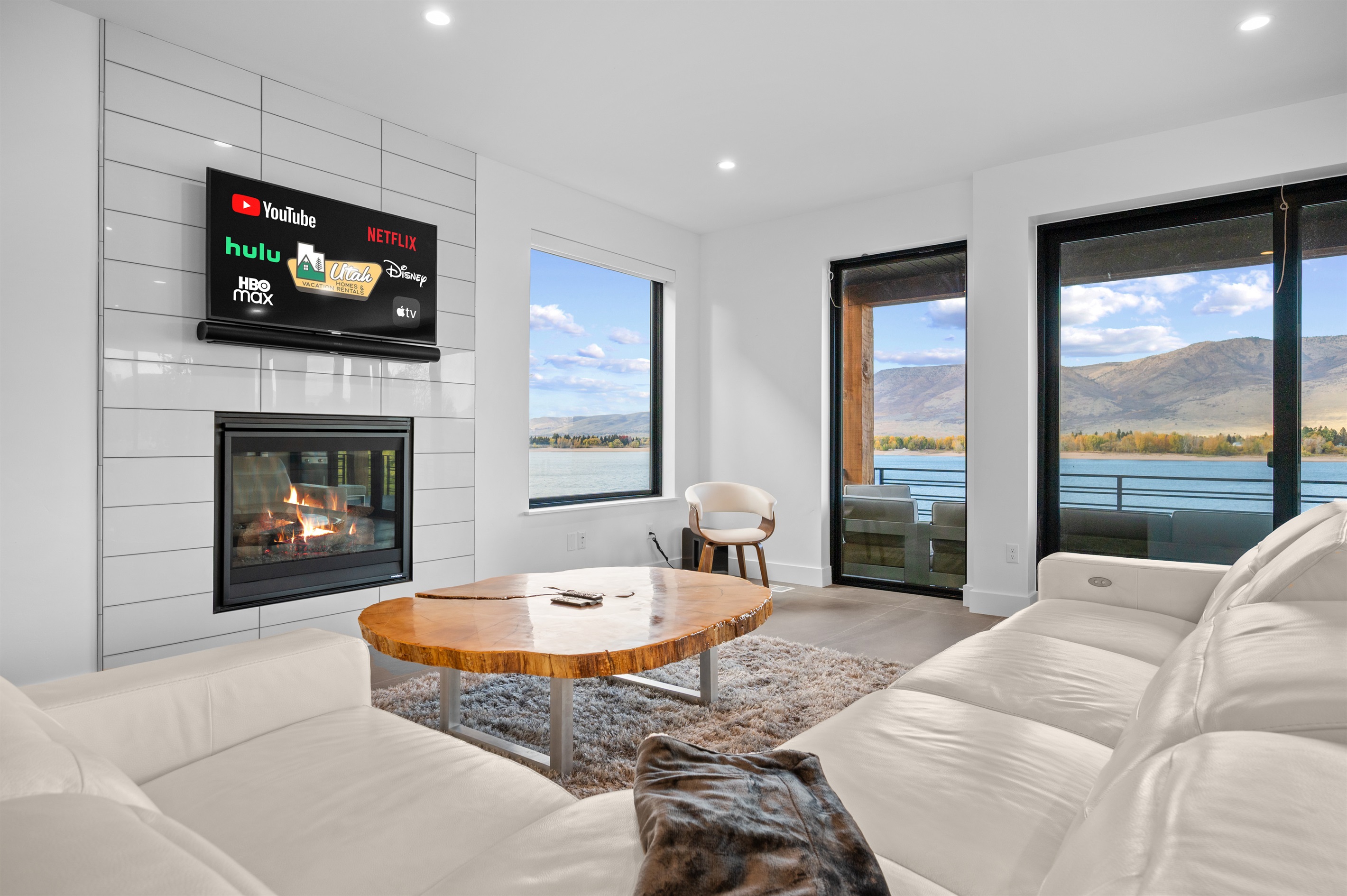Stylish lake-view living room with Smart TV and fireplace.