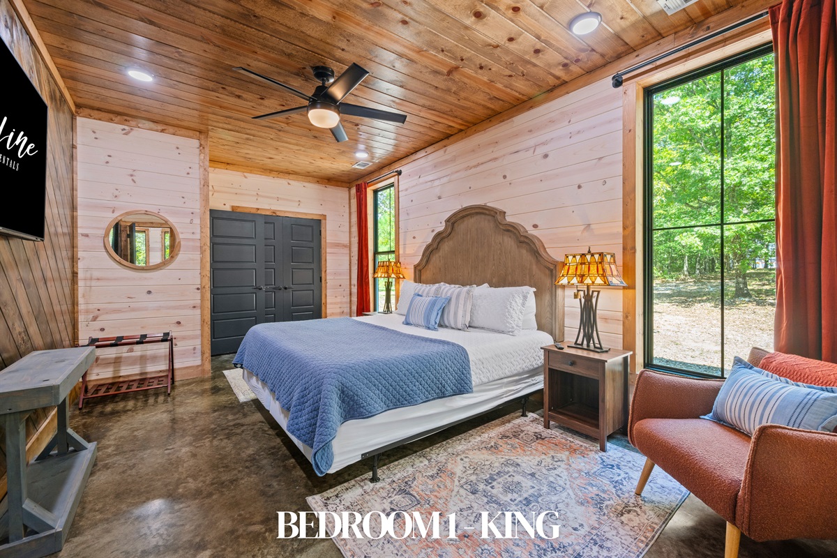 Bedroom 1: King bed with cozy bedding and forest views.