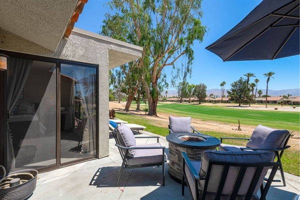 Patio with dining table/firepit and loungers overlooking the golf course