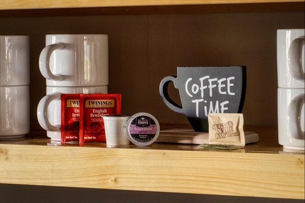 Stocked coffee & tea bar with mugs, sweeteners, and K-cups.