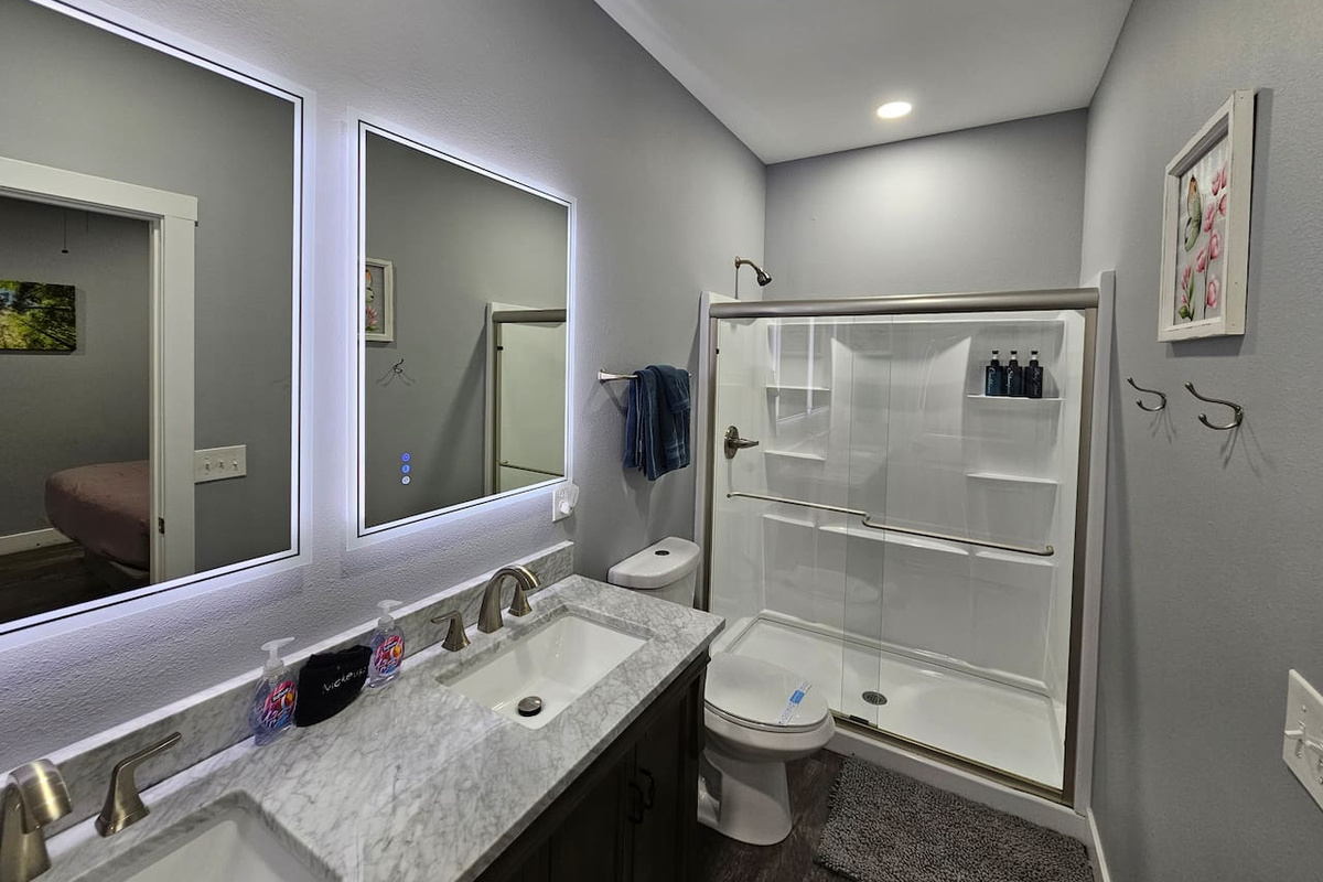 Clean and inviting bathroom with walk in shower, backlit mirrors, and fresh linens provided for your stay.