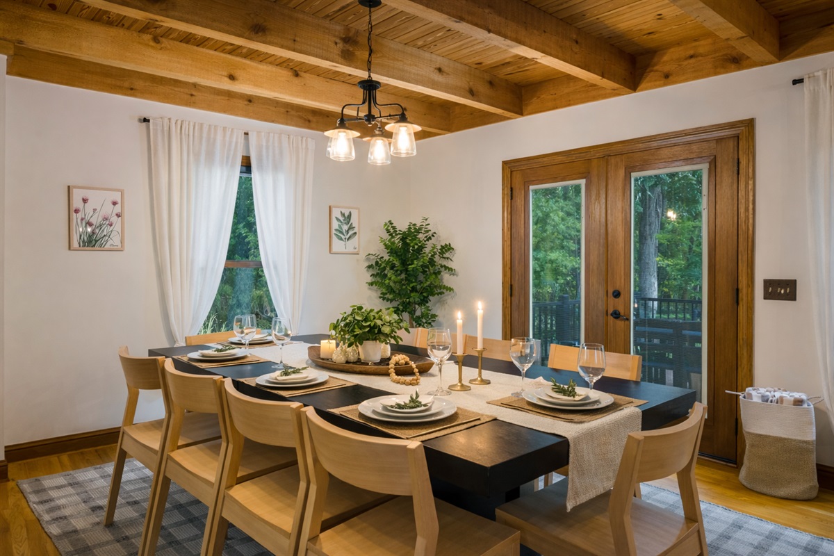 Ten place settings, wine glasses, candles, French doors to the deck behind — the dining room was designed for the kind of dinner that goes three hours.