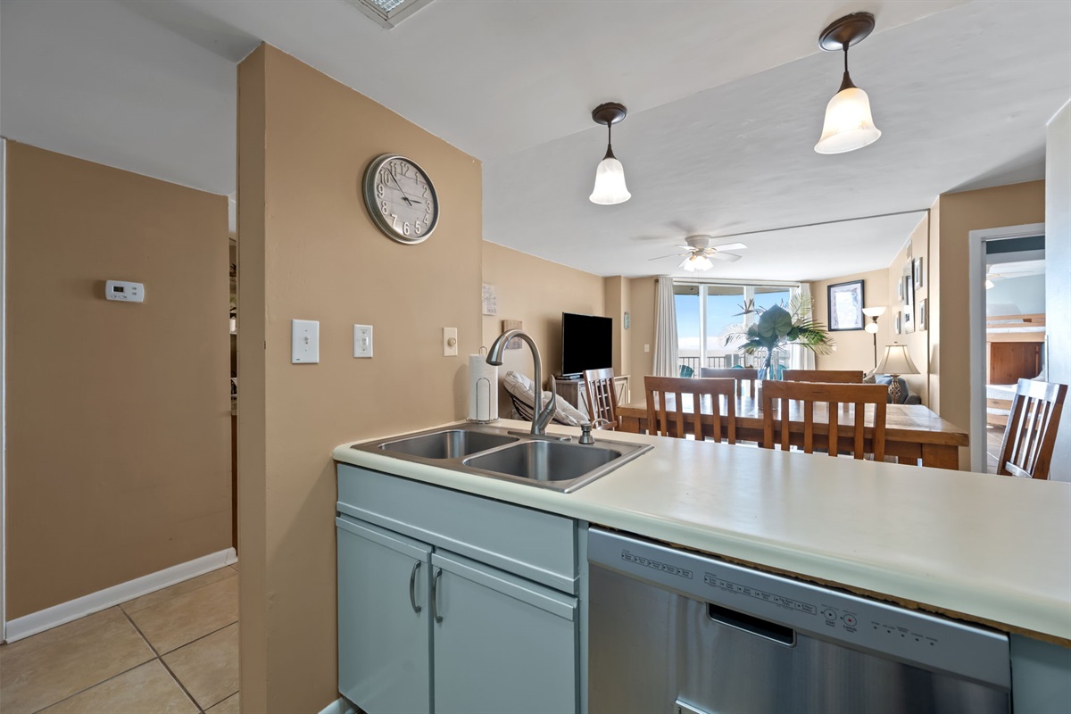 Kitchen pass-through with double sink and dishwasher, offering a clear view into the dining and living areas for easy entertaining