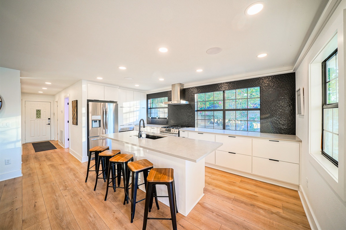 Clean lines and wide-open flow make this kitchen and hallway the heart of the home — stylish, spacious, and ready for group stays.