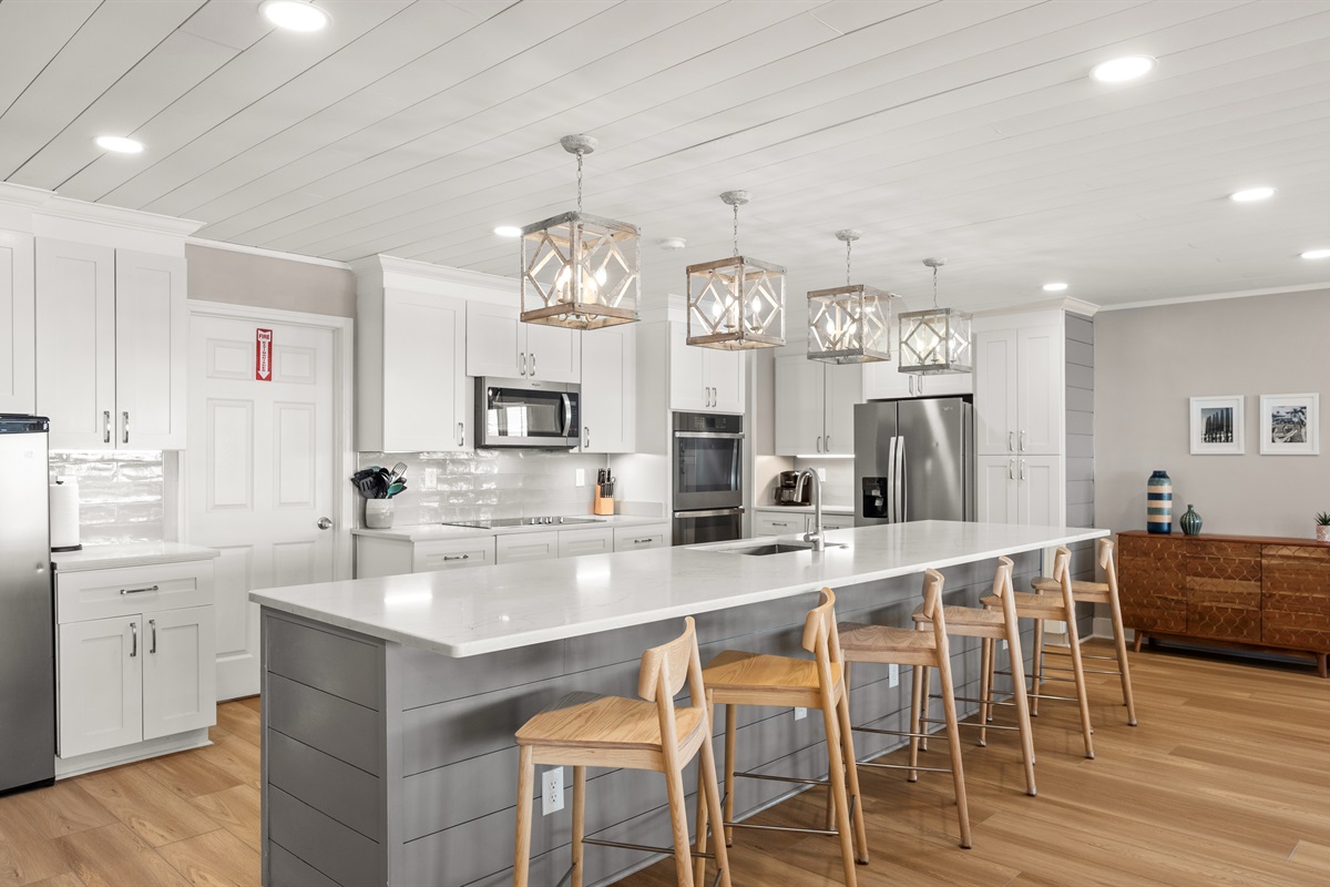 Six barstools complete the function of the 13+ foot quartz countertop and island. A high chair and baby gate are located in the utility closet just behind the ovens.