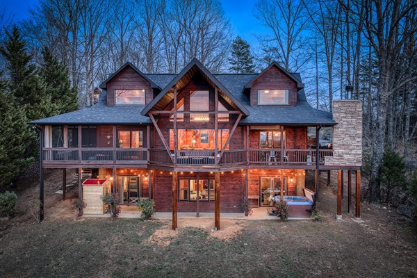 The back of the beautiful "Blessed Sunset" mountain retreat home overlooking the back yard! Stunning A-frame, wrap-around porch, screened-in patio, outdoor fireplace, outdoor dining table, sauna, hot tub, outdoor couch, and more!
