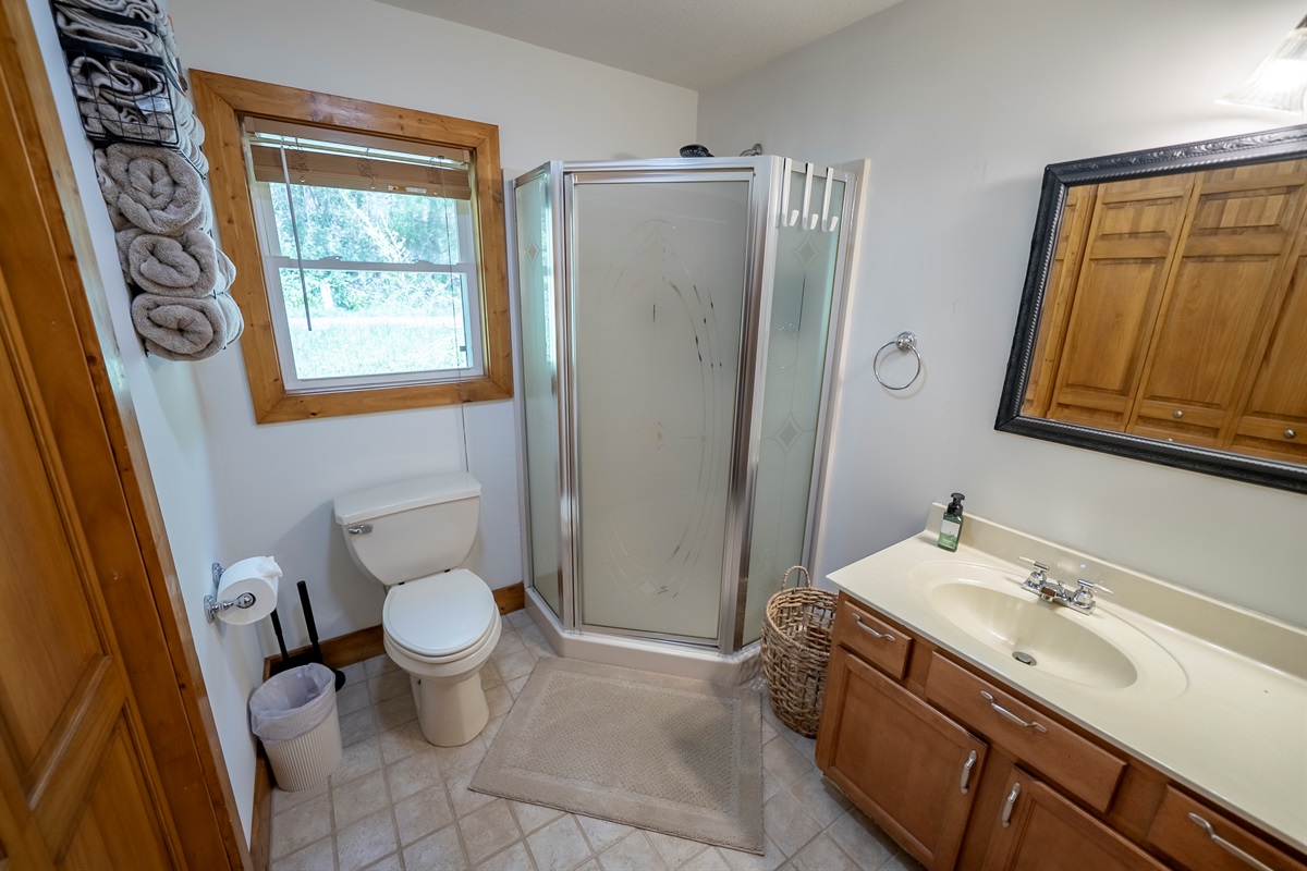 Guest bathroom with a stand-alone shower, vanity, and in-unit laundry for added convenience.